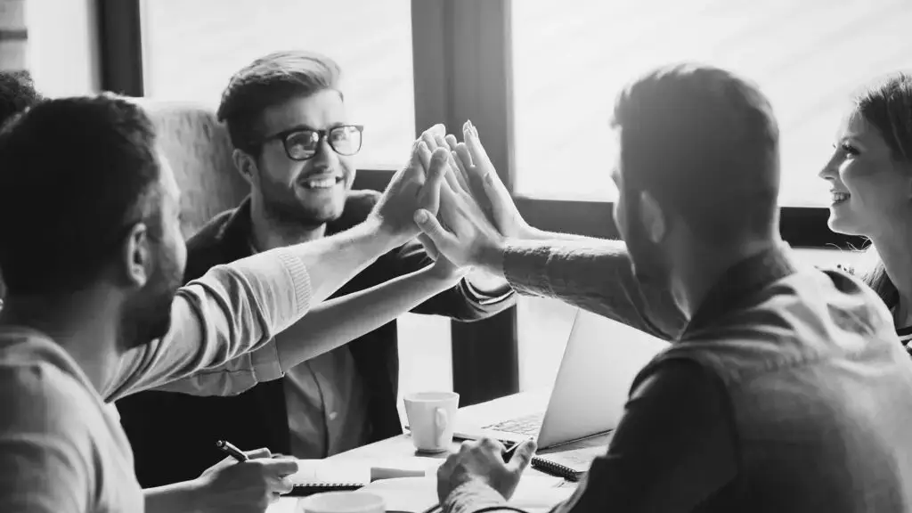 A group of people high-fiving across an office table